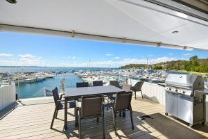 une terrasse avec une table et des chaises et une vue sur le port de plaisance dans l'établissement Crows Nest 6 Teramby Road D Albora Marina, à Nelson Bay