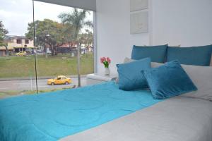 1 cama con almohadas azules en un dormitorio con ventana en Acogedor Apartamento, excelente ubicación. Pereira en Pereira