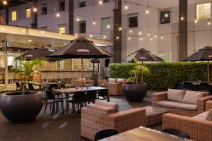an outdoor patio with tables and chairs and umbrellas at Novotel Auckland Ellerslie in Auckland