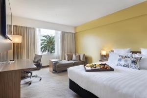a hotel room with a bed with a tray of food on it at Novotel Auckland Ellerslie in Auckland