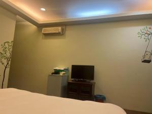 1 dormitorio con 1 cama y TV en la pared en Shan Shui Yan Homestay, en Liugui