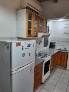 cocina con nevera blanca y armarios de madera en Complejo las Palmeras II en Mendoza