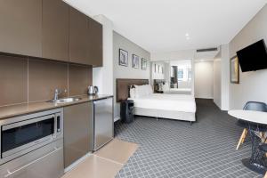 Holiday Inn & Suites Sydney Bondi Junction, an IHG Hotel في سيدني: غرفه فندقيه بسرير ومطبخ
