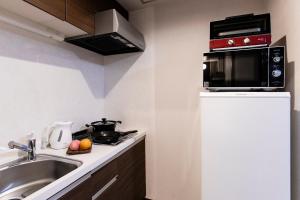 a small kitchen with a sink and a microwave at The Base Sapporo Susukino in Sapporo
