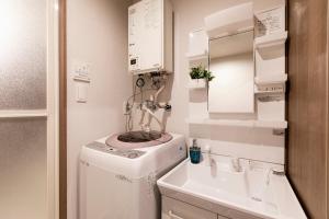 a small bathroom with a washing machine and a sink at The Base Sapporo Susukino in Sapporo +44 photos