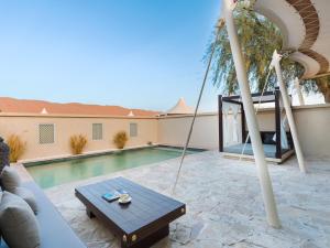 a hammock on a patio next to a swimming pool at Desert Nights Resort - Inclusive of a Free Sunset Drive and Camel Ride in Shāhiq