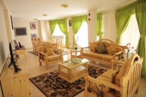 a large living room with green curtains and furniture at Almudena Apart Hotel in La Paz
