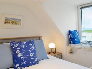 a bedroom with a bed with blue pillows and a window at Pebble Cottage in Port William