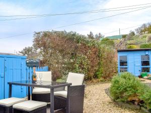 a patio with a table and chairs and a blue building at Pebble Cottage in Port William