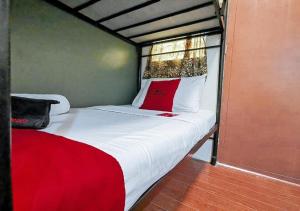 uma cama vermelha e branca num quarto em RedDoorz near KCC Mall Gensan em General Santos