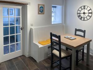 a dining room with a table and chairs and a clock at The White Cottage in Gargrave
