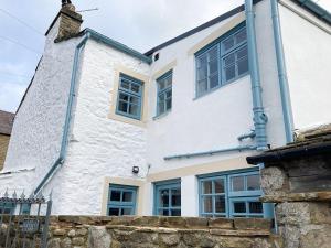 a white house with blue windows and a stone wall at The White Cottage in Gargrave