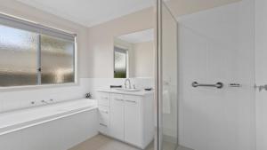 a white bathroom with a sink and a shower at Pelican House in Lakes Entrance +4 photos