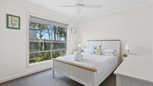 a white bedroom with a bed and a window at Pelican House in Lakes Entrance
