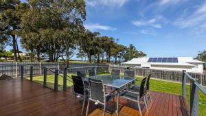 a patio with a table and chairs on a wooden deck at Pelican House in Lakes Entrance