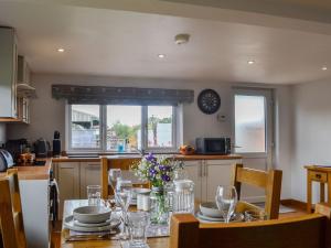 a kitchen with a table with plates and wine glasses at Hillside Cottage in Hanmer