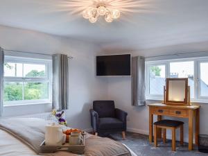 a bedroom with a bed and a chair and a tv at Hillside Cottage in Hanmer