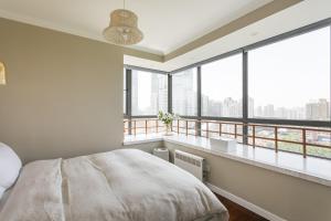 a bedroom with a bed and a balcony with windows at Xujiahui park 2BR Apt in Shanghai