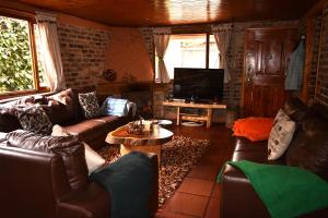 a living room with leather couches and a tv at Acogedora Cabaña En Tabio con zonas verdes y BBQ in Tabio