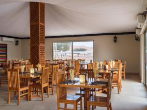 a dining room with wooden tables and chairs at Desert Nights Resort in Shāhiq