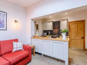 a living room with a red couch and a kitchen at Lambton Cottage in Grosmont