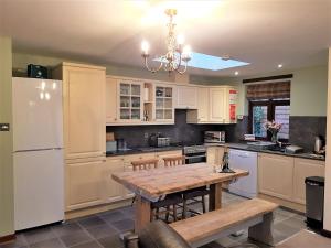 a kitchen with a wooden table and a white refrigerator at Trebor Cottage in Annan