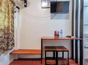 a table and stool with a television on a wall at RedDoorz near KCC Mall Gensan in General Santos