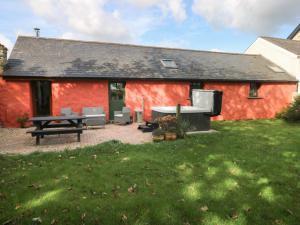 a red building with a picnic table and chairs at Blueberry Cottage in Haverfordwest