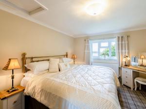 a bedroom with a white bed and a window at Hampsfell Cottage - Uk1518 in Grange Over Sands