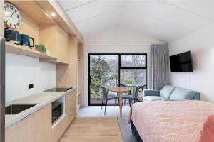 Driftaway Queenstown في كوينزتاون: غرفة نوم بسرير ومطبخ مع طاولة