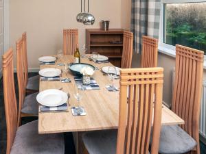 a dining room table with chairs and a table with plates and wine glasses at Longmead in Berry Pomeroy