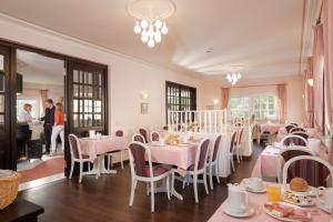 a dining room with pink tables and chairs and people at Hotel Heuboden in Umkirch