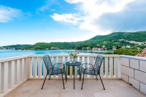 a table and chairs on a balcony with a view of the water at Villa Kukuljica in Zaton