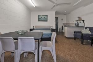 Balgal Beach Units في Rollingstone: غرفة بسرير وطاولة وكراسي