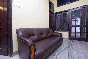 a brown leather couch sitting in a room at Flagship Greenview Near Munshi Pulia Metro Station in Vibhuti Khand