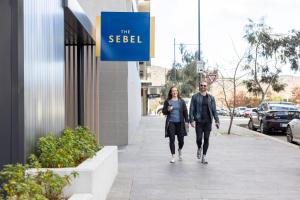 a man and a woman walking down a sidewalk at The Sebel Canberra Campbell in Canberra