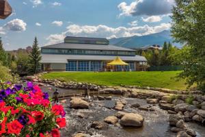 a building with a river and flowers in front of it at The Corral at Breckenridge by Summit County Mountain Retreat in Breckenridge