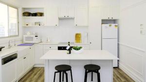 a kitchen with white cabinets and a white island with two stools at Longford Faulkland in Gloucester