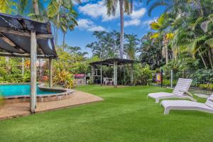 a lawn with white chairs and a swimming pool at Balgal Beach Units in Rollingstone