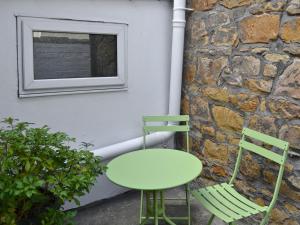 una mesa verde y dos sillas junto a una pared en Joellen Cottage, en Alnwick