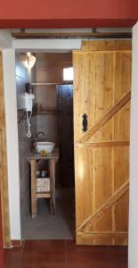 a bathroom with a wooden door and a sink at La Comarca in Uspallata