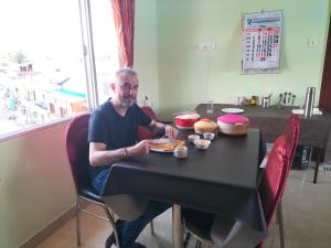 um homem sentado à mesa com um prato de comida em CITY VIEW em Port Blair