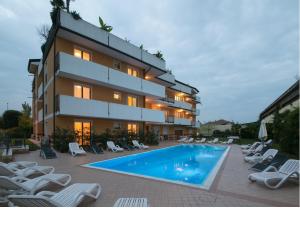 a building with a swimming pool and lounge chairs at Ferretti Residence Garda Palace in Peschiera del Garda