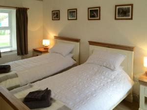 two twin beds in a bedroom with two lamps at Cauldside West Cottage in Whitekirk