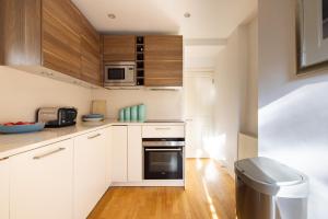 eine Küche mit weißen Schränken und einem schwarzen Backofen in der Unterkunft NIRU Experience Huge Private Terrace In Chelsea in London