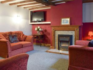 a living room with a fireplace and a tv at Richmond Cottage in Ashby Saint Ledgers