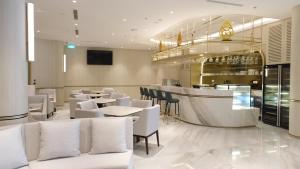 un restaurante con mesas y sillas blancas y un bar en Atria Hotel Gading Serpong, en Serpong