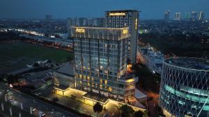 a night view of a tall building with lights on at Atria Hotel Gading Serpong in Serpong