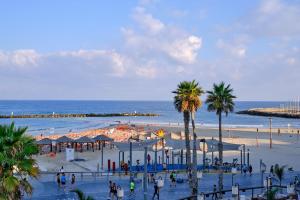 a beach with people and palm trees and the ocean at Beautiful 2-bedroom condo in the heart of Tel Aviv in Tel Aviv