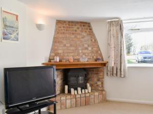 a living room with a brick fireplace with a tv at Kings Cottage in Combe Martin